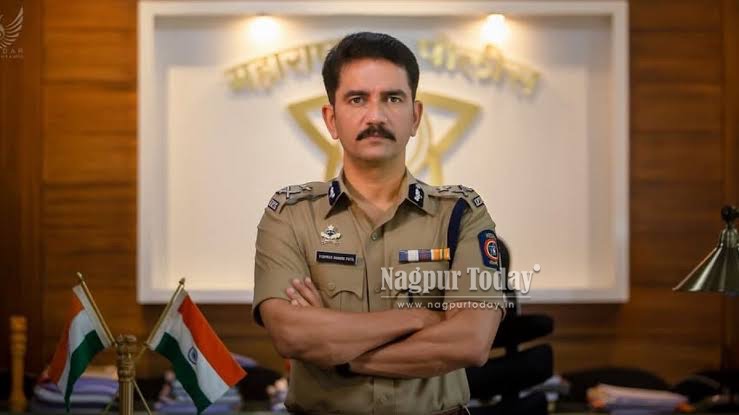 Vishwas Nangre Patil standing with arms folded in front of the Maharashtra Police emblem